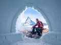 Un uomo ammira il maestoso Cervino dall'interno di un igloo, un'esperienza unica di dormire in un igloo in Italia.