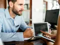 Receptionist con tablet mostra a cliente che non ci sono più camere, un caso di overbooking hotel.