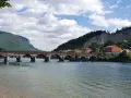 Ponte storico sul fiume Adda, con montagne verdi e case colorate. Un'ottima vista per scoprire cosa vedere a Calolziocorte.