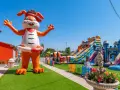 Gigante coniglio gonfiabile "Ciccio" accoglie i bambini in un parco giochi con scivoli e castelli gonfiabili, un'oasi di divertimento per gli ospiti dell'hotel Ciccio.