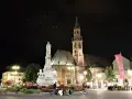 Piazza Walther di Bolzano di notte: la cattedrale, il monumento e la bandiera rossa. Un'idea di cosa vedere a Bolzano in un giorno.
