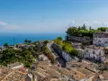 Panoramica di un borgo collinare con vista mare. Per raggiungere l'università Monte Sant'Angelo Napoli, si percorre una strada tortuosa tra case antiche.