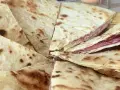 Piadina sfogliata ricetta originale, con strati sottili e ripieno di salumi, pronta per essere gustata.