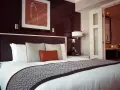 Letto in una camera doppia, con copriletto geometrico e quadro astratto. Il significato di camera doppia è un luogo accogliente.