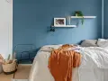 Camera da letto moderna con letto, coperta arancione, cestino e sedia in metallo. Utile per la classificazione camere hotel.