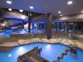 Piscina interna con scivoli acquatici e giochi d'acqua al Quellenhof Merano, un'oasi di divertimento e relax.