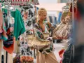 Un ragazzo con treccine bionde sceglie borse in un mercato di shopping a Roma.