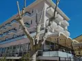 Edificio moderno con balconi e vetrate, un albero spoglio in primo piano. Il **Kursaal Bellaria** si presenta sotto un cielo azzurro.
