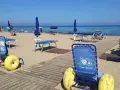 Carrozzine speciali e passerelle per vacanze per disabili con assistenza su una spiaggia attrezzata.