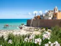 Vista di una spiaggia affollata con un trabucco sul mare e il borgo antico di Termoli. Perfetto per scoprire cosa vedere vicino a Termoli.