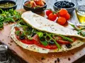 Piadina ripiena con pomodoro, mozzarella filante, rucola e olive nere. Un'esplosione di sapori per le tue farciture per piadine.