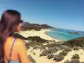Vista mozzafiato di una spiaggia sarda, con dune sabbiose e macchia mediterranea. Perfetta per le gite in Sardegna.