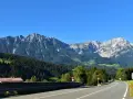 Strada panoramica per viaggi in auto in Europa dall'Italia, con montagne imponenti e boschi verdi.