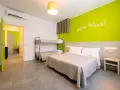 Camera luminosa con letto matrimoniale, letto a castello e parete verde brillante. Un invito a godersi i colori del green village Cesenatico.
