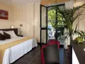 Camera accogliente al Park Hotel Kursaal Misano, con letto comodo, piante verdi e valigie rosse pronte per la partenza.