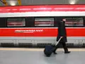 Uomo con bagagli ingombranti cammina lungo il Frecciarossa 1000.