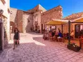 Una donna cammina in un vicolo di Santo Stefano di Sessanio, dove si trovano i migliori ristoranti. Tavoli all'aperto invitano a gustare la cucina locale.