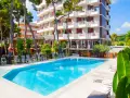 Piscina azzurra e lettini prendisole davanti al **promenade hotel giulianova**, circondati da pini e vegetazione lussureggiante.