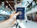Passaporto USA e boarding pass pronti per il viaggio. L'aeroporto fa da sfondo.
