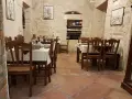 Atmosfera intima per scoprire dove cenare a Lecce: tavoli apparecchiati in pietra leccese, bottiglie di vino e quadri d'epoca.