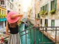 Una donna con cappello rosa ammira un canale a Venezia, un'esperienza indimenticabile di "Venezia in un giorno a piedi".