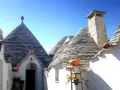 Trulli con zucche arancioni nel centro storico di Alberobello, sotto un cielo azzurro.