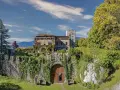 Villa d'Ayala, un castello incantevole con torri e giardini lussureggianti, immerso tra le montagne sotto un cielo azzurro.