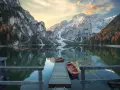 Lago di Braies, con montagne innevate e boschi autunnali riflessi sull'acqua. Per sapere come arrivare al lago di Braies in treno da Roma, cerca online.