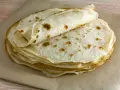 Impasto piadina appena cotto, impilato su carta da forno. Le sottili sfoglie dorate invitano a essere farcite.