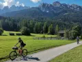 Ciclisti lungo la ciclabile San Candido Lienz, tra prati verdi e montagne maestose. Un'avventura di chilometri immersi nella natura.