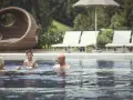 Famiglia felice si diverte in piscina al Cavallino Bianco Family Spa Grand Hotel. Relax e gioia per tutti.
