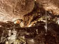 Sentiero illuminato tra stalattiti e stalagmiti in una delle magnifiche grotte in Italia. Un viaggio sotterraneo mozzafiato.