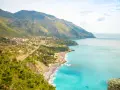 Panoramica di una costa montuosa con un villaggio affacciato sul mare turchese. Perfetto per itinerari Basilicata in macchina.