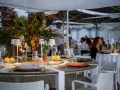 Tavoli apparecchiati sulla spiaggia di Riccione, con limoni, rose rosse e piccole lampade. Atmosfera serale, perfetta per una cena di manna.