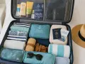 Valigia aperta con abiti piegati, creme solari, cappello di paglia, occhiali da sole e documenti. Ecco cosa portare in barca a vela per una vacanza perfetta.