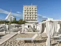 Spiaggia attrezzata con lettini e gazebo bianchi, sullo sfondo l'imponente hotel Abners.