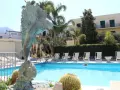 Scultura di pesce e piscina invitante al **hotel Punta del Sole Ischia**, circondata da palme e lettini.