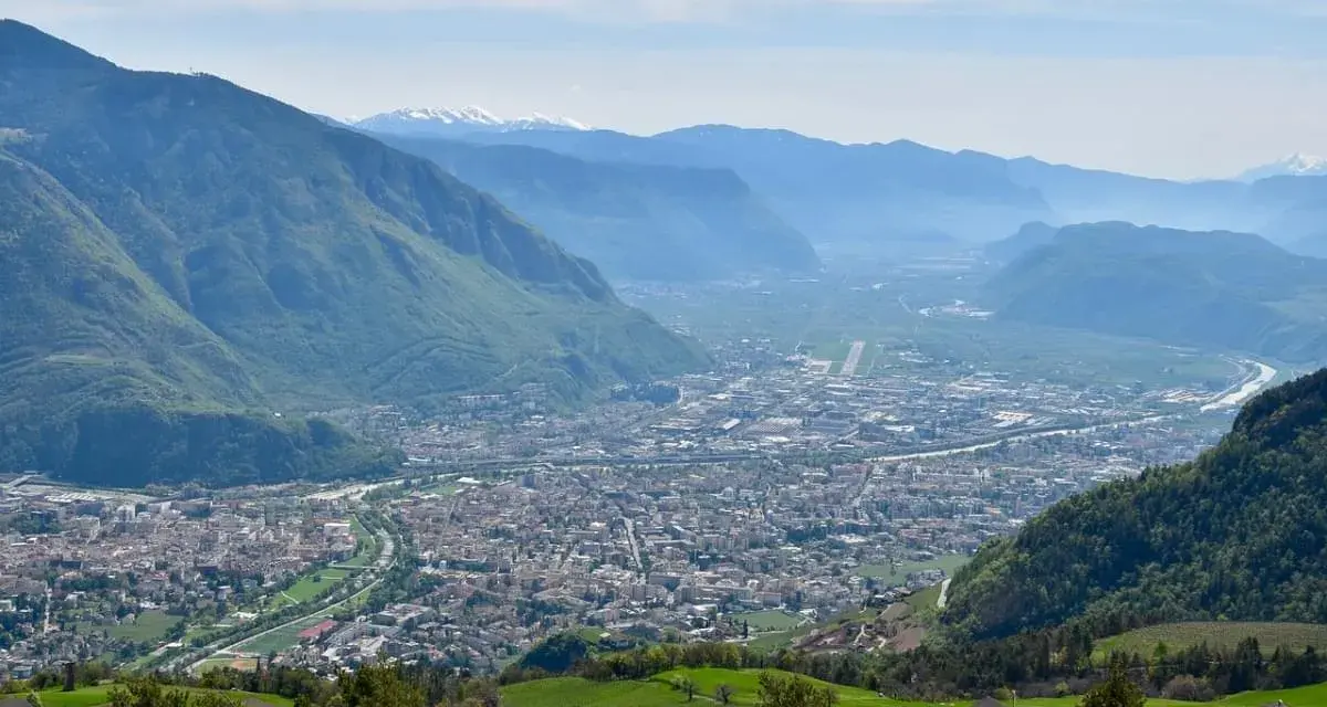Vista panoramica di Bolzano e della valle, con montagne verdi e innevate sullo sfondo. Perfetto per scoprire cosa fare a Bolzano in un giorno.