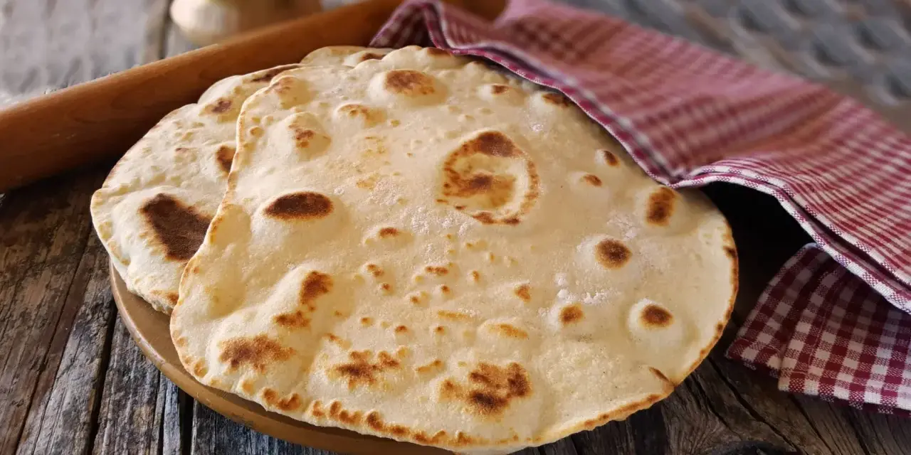 Piadine pronte per essere farcite, con un matterello e un canovaccio a quadretti. Si può fare l'impasto della piadina il giorno prima per comodità.