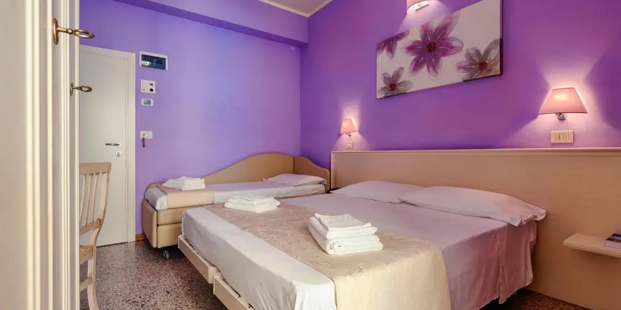 Camera accogliente con letti comodi e pareti viola, ideale per un soggiorno rilassante al Hotel Plaza Gabicce Mare.