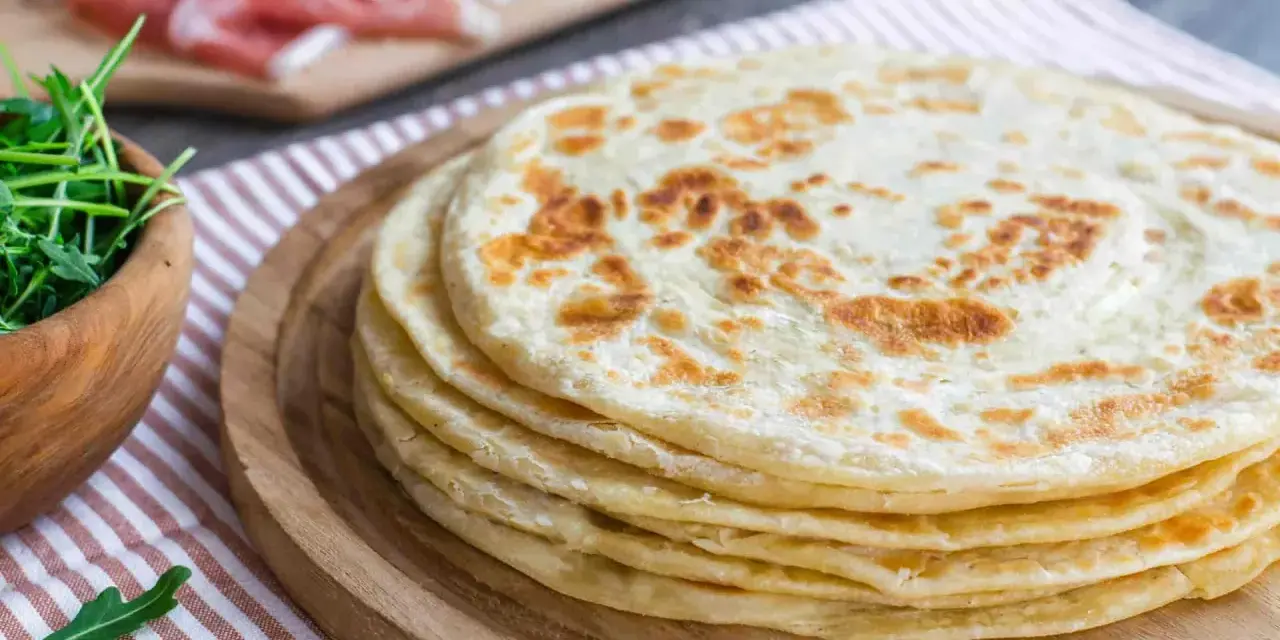 Pila di piadine marchigiane, pronte per essere farcite con rucola e salumi.