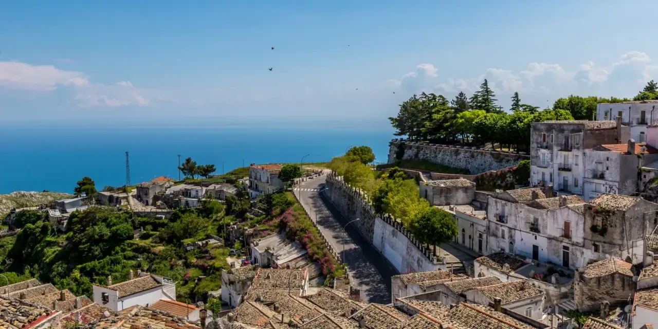 Panoramica di un borgo collinare con vista mare. Per raggiungere l'università Monte Sant'Angelo Napoli, si percorre una strada tortuosa tra case antiche.