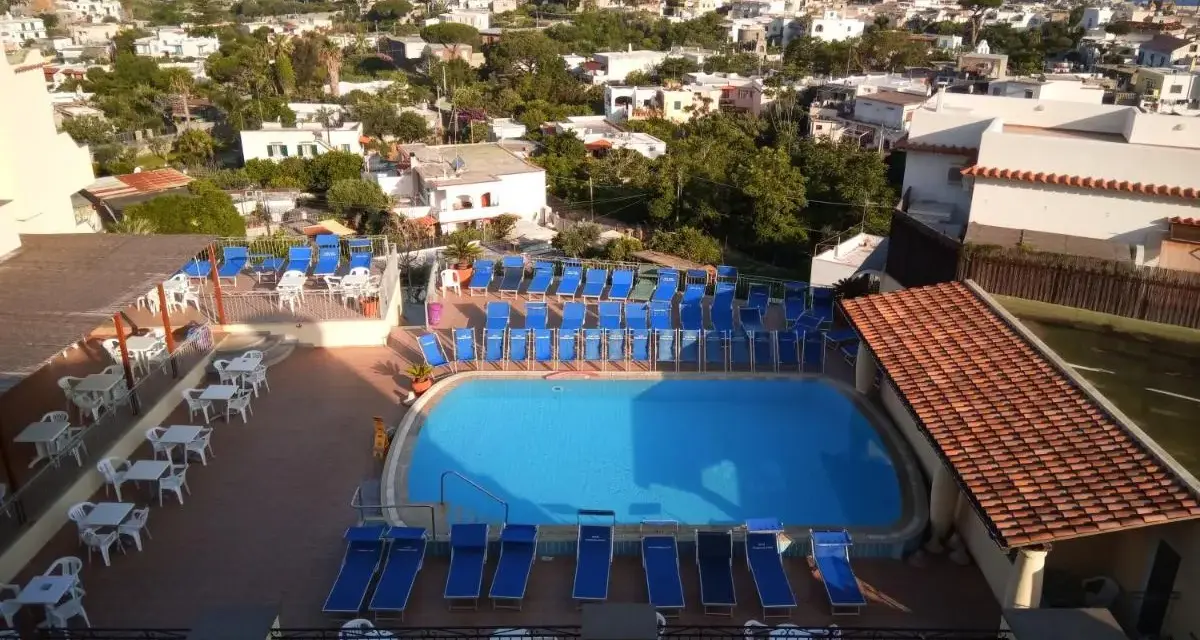 Piscina e lettini prendisole al **hotel tramonto Ischia**, con vista sul mare e sul paese.