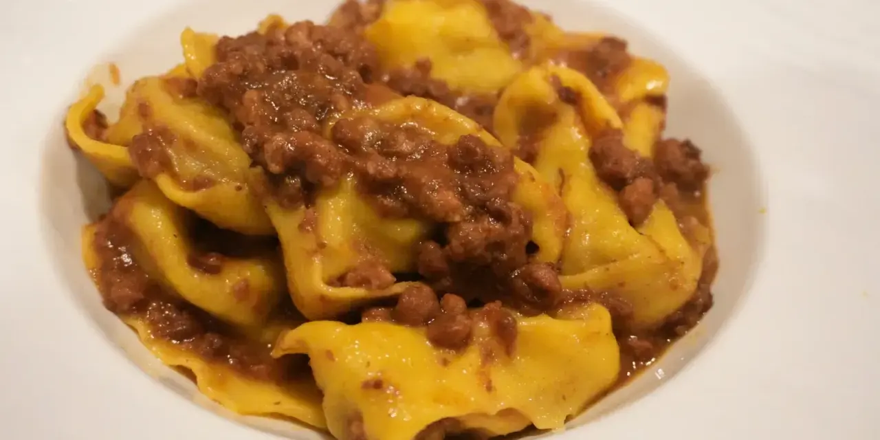 Tortellini fatti in casa con ragù, un classico dei primi piatti romagnoli.