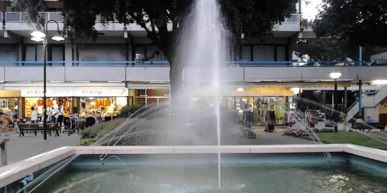 Fontana z fontanną w centrum Lido di Savio, z widokiem na sklepy i drzewa.