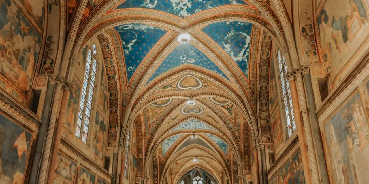 Volte affrescate con cielo stellato e scene sacre nella Basilica Superiore di San Francesco, cuore del centro storico di Assisi.