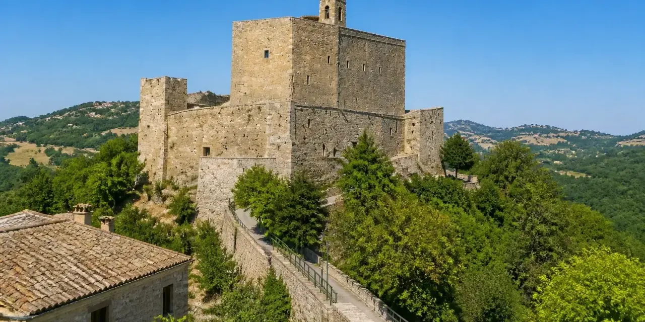Rocche imponenti e case in pietra a Montefiore Conca, circondate da verdi colline sotto un cielo azzurro.