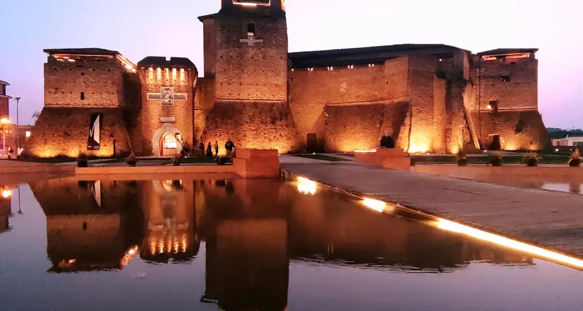 Castello illuminato di sera, riflesso sull'acqua. Un luogo magico che evoca il mondo di Fellini.