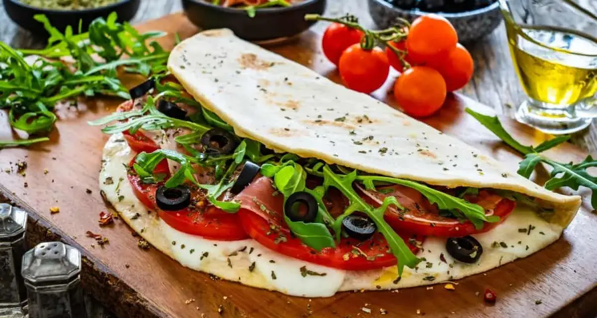 Piadina ripiena con pomodoro, mozzarella filante, rucola e olive nere. Un'esplosione di sapori per le tue farciture per piadine.