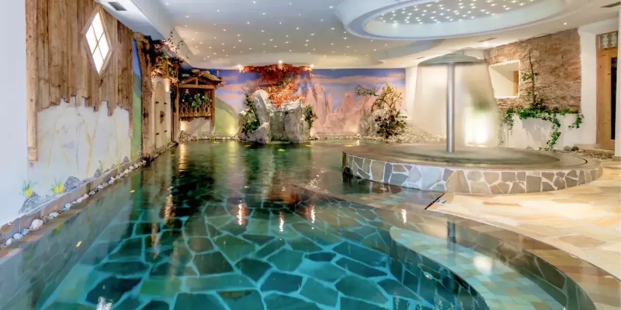 Piscina interna con cascata e decorazioni naturali, un'oasi di relax all'Hotel Sporting Andalo.